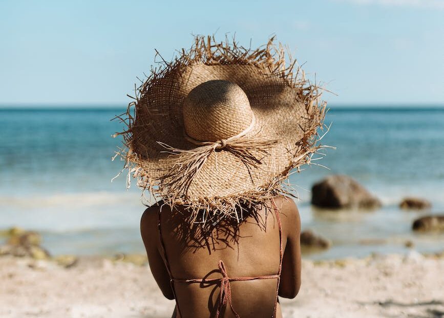 woman in bikini sitting on sand beach