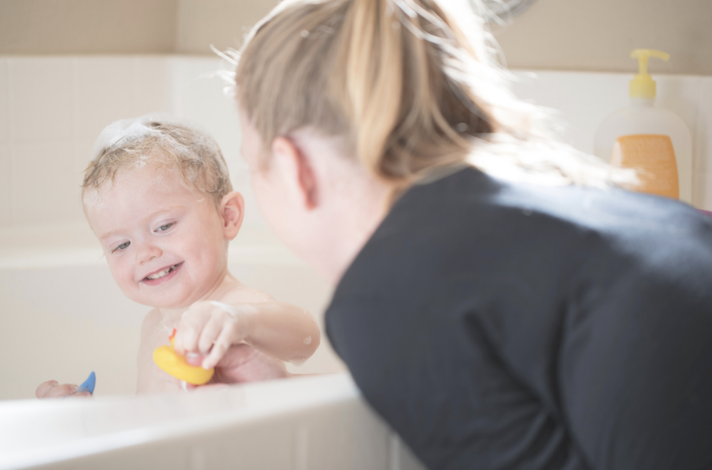 niño feliz en la bañera jugando con jabón natural 
