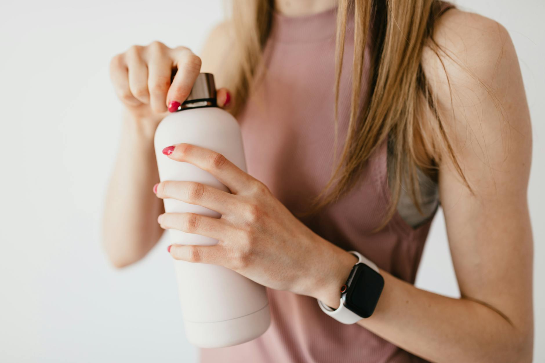 anonymous young woman opening cosmetic bottle